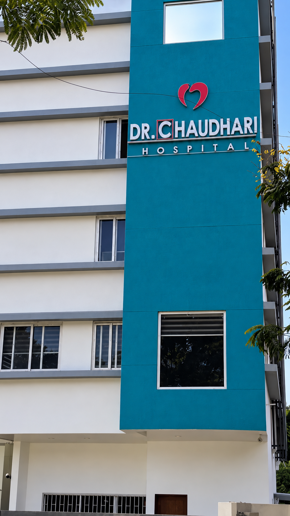 Teal tower of Dr. Chaudhari Hospital displaying the hospital name and heart emblem
